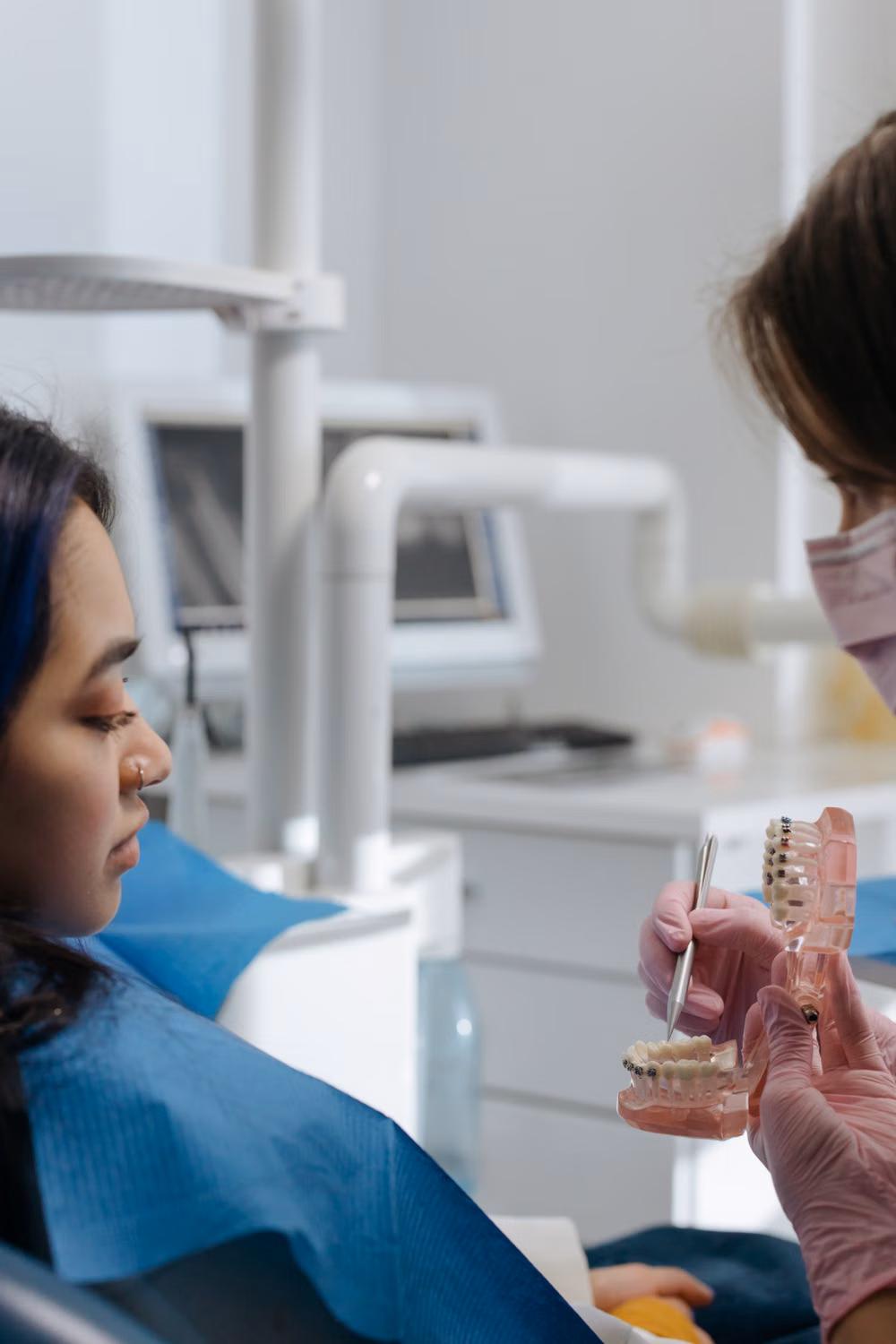 Profesional dental explicando un tratamiento a una paciente con un modelo dental